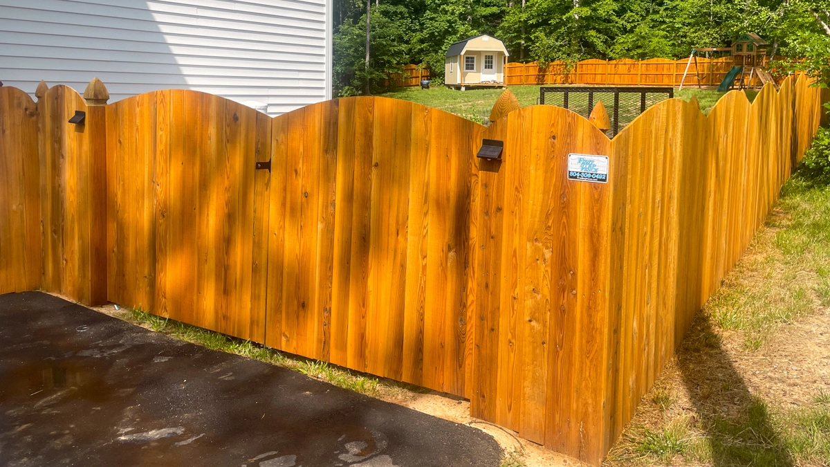 A freshly stained wooden fence surrounding a residential yard. First Step Fence offers expert wood fence installation and staining to Richmond Virginia and the surrounding areas.