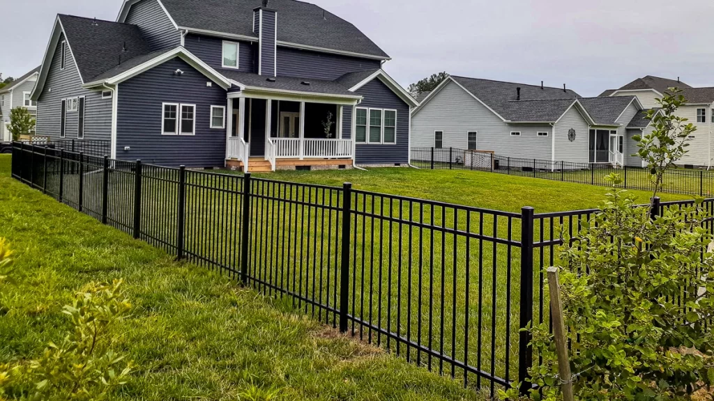 A black aluminum fence surrounding a backyard. First Step Fence aluminum fences add timeless elegance to any home.