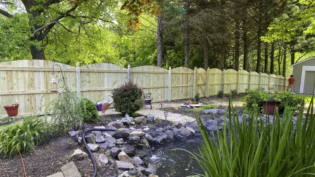 A tall wooden privacy fence with double gates, offering security and privacy for a backyard. First Step Fence builds durable residential wood fences.