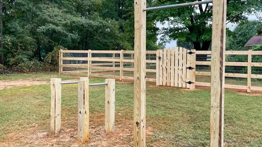 A decorative wood fence surrounding a landscaped backyard, featuring a mix of stone and wood for a stylish look. First Step Fence creates custom wood fences.