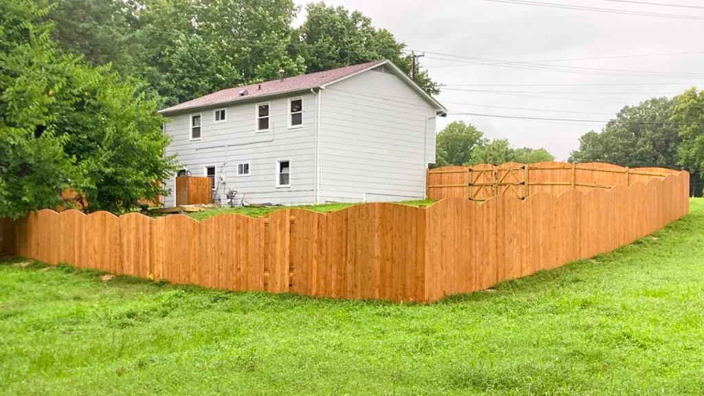 A residential property surrounded by a scalloped wood fence. First Step Fence highlights the natural beauty and timeless appeal of wood fencing.