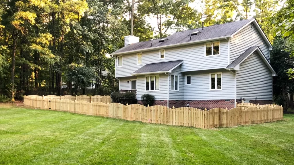 A charming wooden picket fence enclosing a front yard, adding a classic touch to the home's exterior. First Step Fence delivers timeless wood fencing solutions.