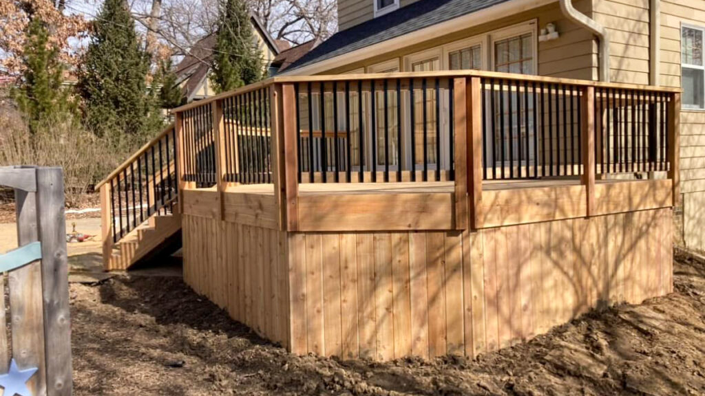 A spacious and elevated wood deck with railings, offering an affordable outdoor living space. First Step Fence provides budget-friendly wood deck solutions.