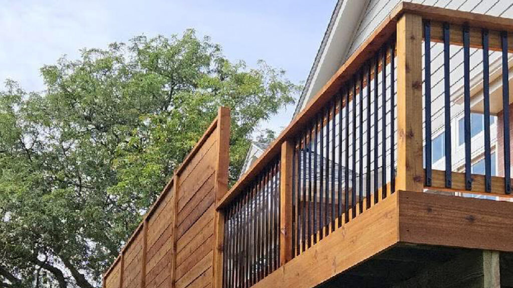 A sturdy wood deck with black metal railings, showcasing its robust construction. First Step Fence builds durable wood decks designed to last.