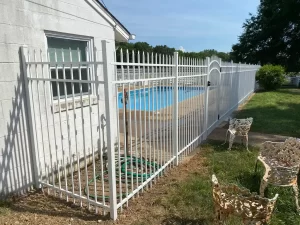 A 6 foot tall white spear top aluminum pool fence on concrete.