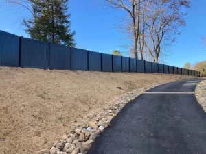 A black vinyl privacy fence giving privacy up a driveway.