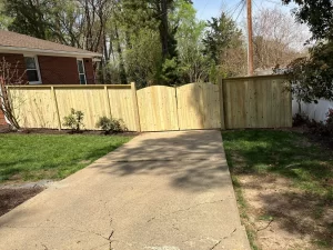 A cap and trim wood fence with a 12 foot wide double gate across the driveway.