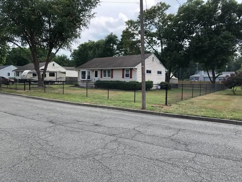 A street view of a residential property surrounded by a black vinyl-coated chain link fence. First Step Fence installs chain link fencing to improve security of residential properties in Richmond, VA and the surrounding areas.