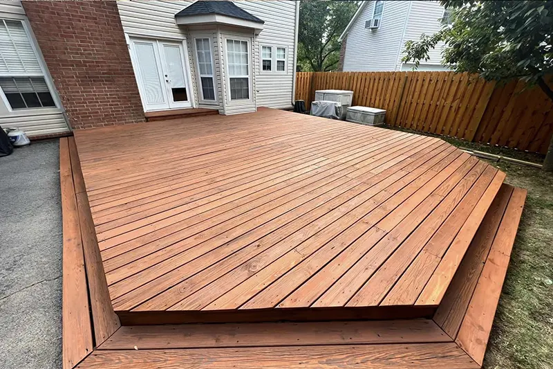 A stained wooden deck. First Step Fence offers exterior wood staining to Richmond, VA and the surrounding areas.