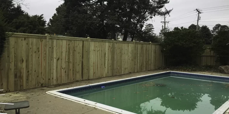 A photo of a wood privacy fence surrounding a backyard pool.